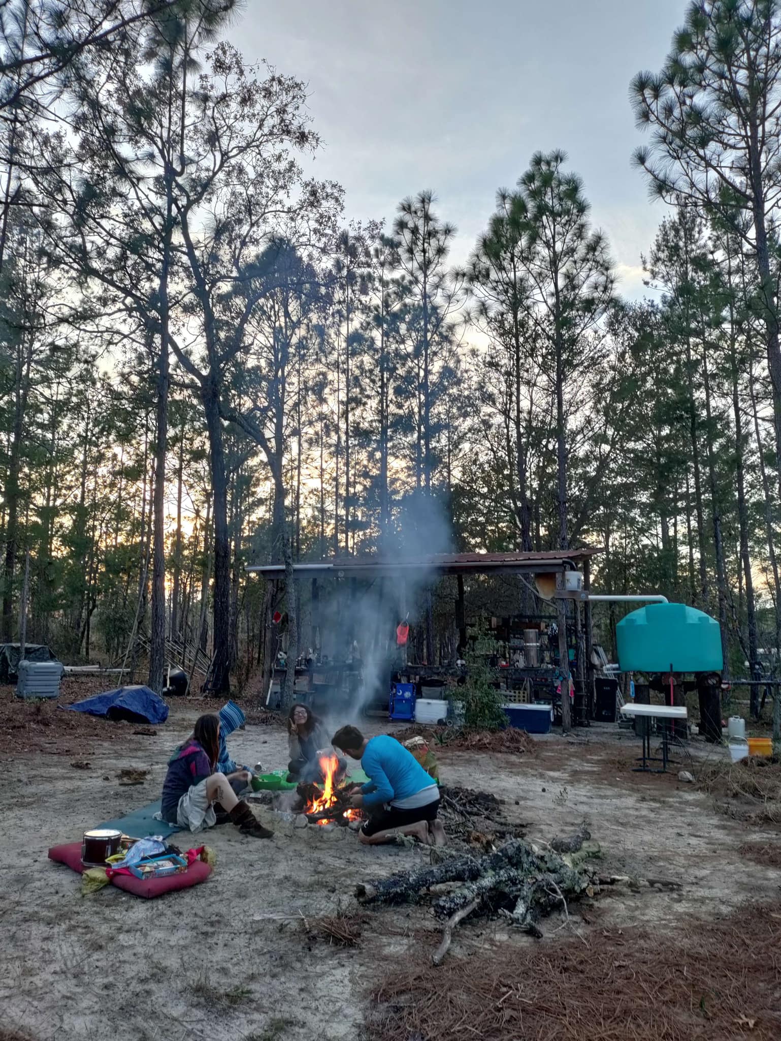 The meme depicts a group of people sitting around a campfire in a forest, with a sign that reads "Beware of the Bears". The image is humorous because it's a typical campsite warning sign, but the people in the image are all clearly adults, not children, and are engaged in adult activities like drinking and playing music.